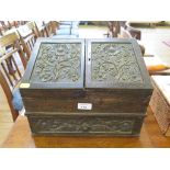 A late Victorian carved oak stationery box, the sloping twin hinged lid carved with sunflowers,