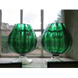 A pair of lobed globular green glass vases on pedestal feet, 25.5cm high