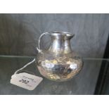 A silver cream jug with hammered decoration