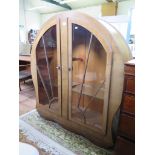 An Art Deco walnut display cabinet of arched sunburst form with twin glazed doors 121cm wide