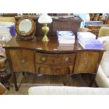 A George III style mahogany serpentine sideboard, the two central drawers flanked by cupboard
