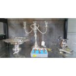 A collection of silver plate to include a swing handle basket, a two branch candelabra, a toast