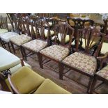 A set of four late George III mahogany shield back dining chairs with pierced vase shape splats,