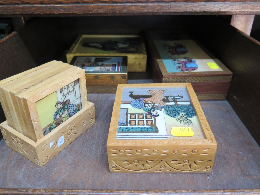 A collection of three boxes and a set of six mats all with coloured gem stone painted scenes of