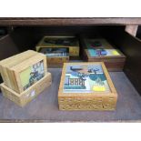 A collection of three boxes and a set of six mats all with coloured gem stone painted scenes of