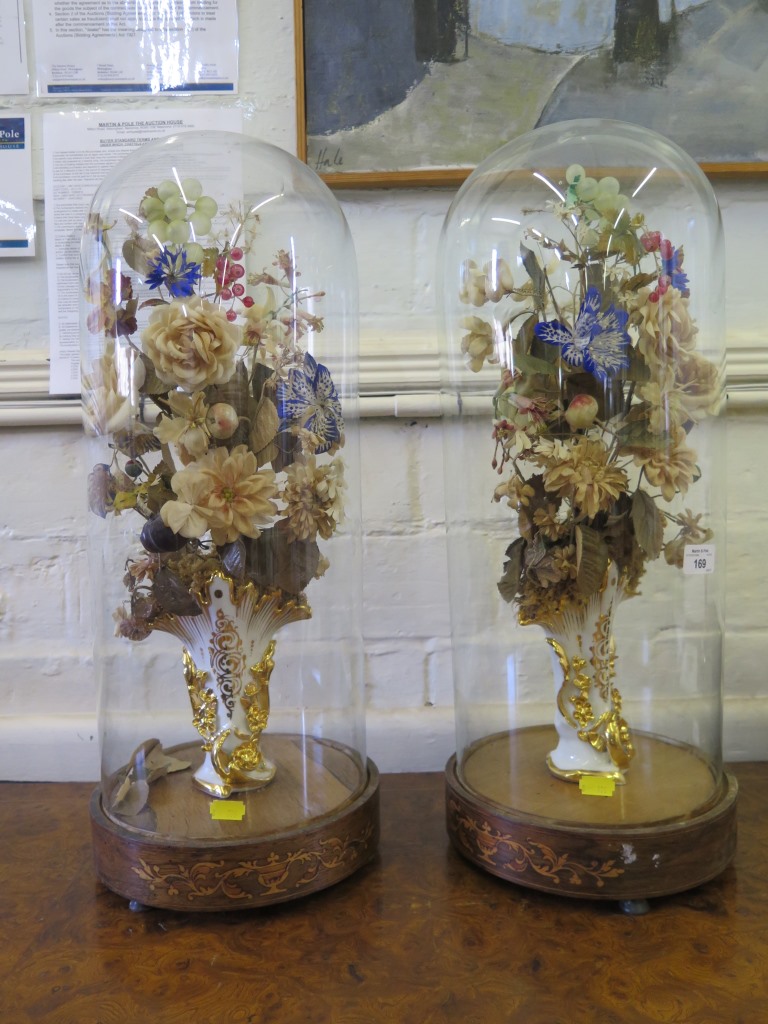 A pair of Edwardian fabric floral displays with gilt vases under glass domes and inlaid circular