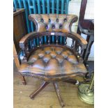 A brown leather button upholstered swivel captain's desk chair, on four downswept legs and castors