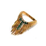 A gold colour metal ring set with six emeralds