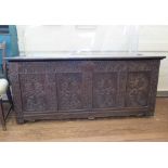 An 18th century oak coffer, the hinged lid over a later carved four panel front, 164cm wide, 59cm