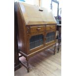 An oak bookcase, with twin glazed and panelled doors 74.5cm wide and an oak bureau with twin drawers