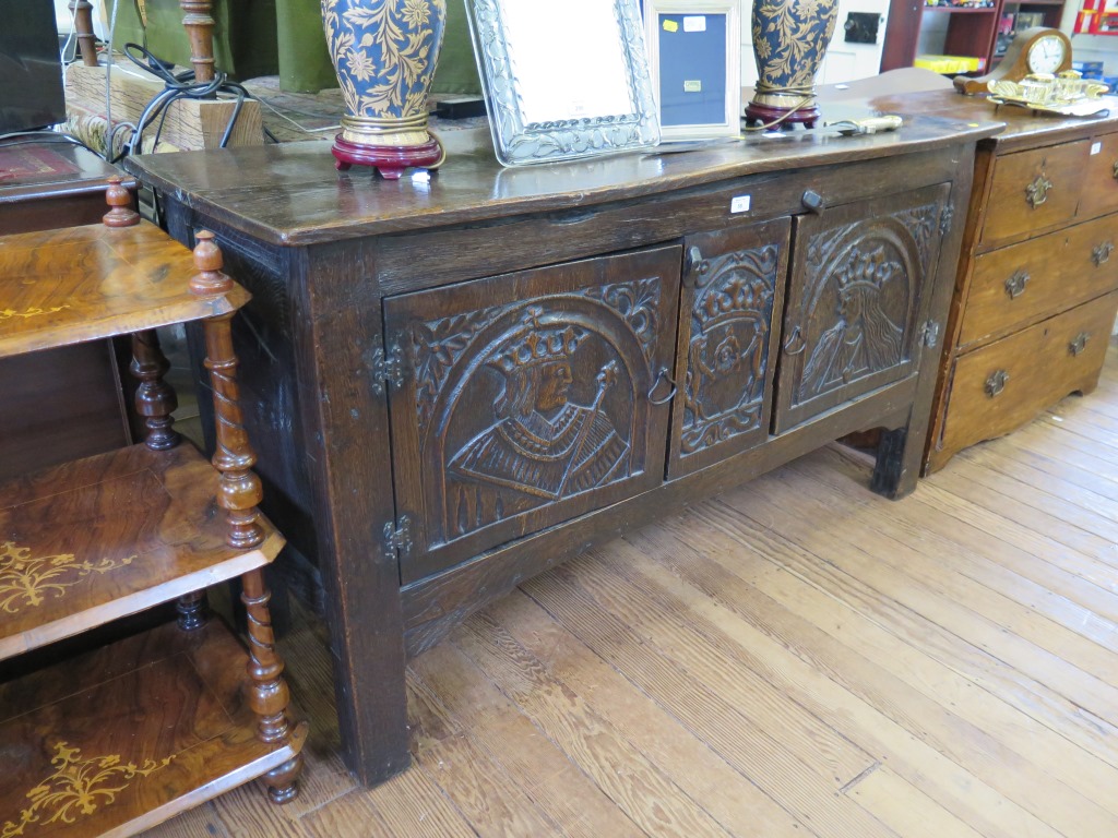 An oak side cabinet, in the form of a coffer, the doors carved with a king and queen flanking a