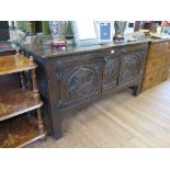 An oak side cabinet, in the form of a coffer, the doors carved with a king and queen flanking a