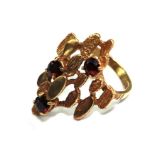 A 9 carat gold ring of bark finnish set with four garnets