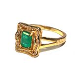 An emerald ring set in gold colour metal