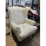 An upholstered wing armchair, with cabriole legs