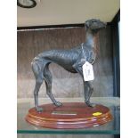 A bronzed figure of a greyhound with one leg raised, 26cm high