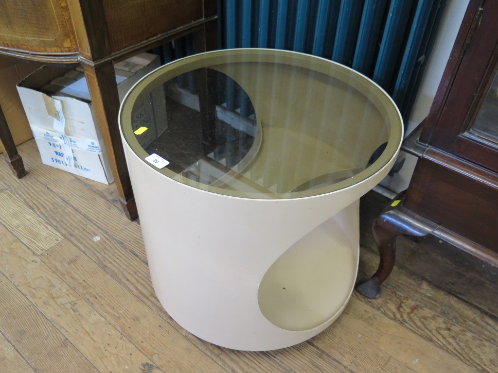 A 1970s fawn plywood circular occasional table, with glass top and concave shelves 54cm diameter