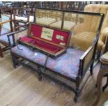 A 1920s oak and cane two seat settee, with overstuffed seat on turned and block legs with carved