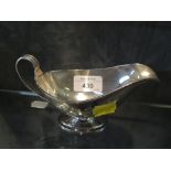 A silver sauce boat on ribbed single foot