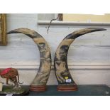 A pair of Eastern carved buffalo horns, depicting dragons and birds with glass eyes, 45cm high