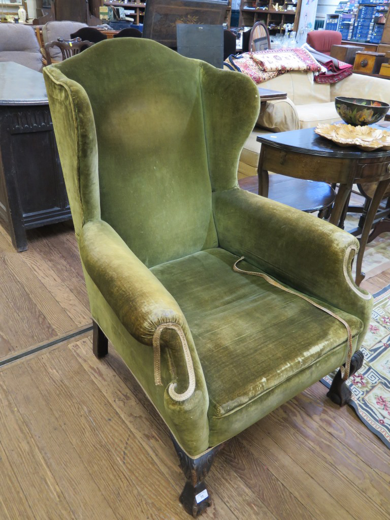 A George III style green upholstered wing armchair with acanthus carved cabriole legs and ball and