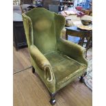 A George III style green upholstered wing armchair with acanthus carved cabriole legs and ball and