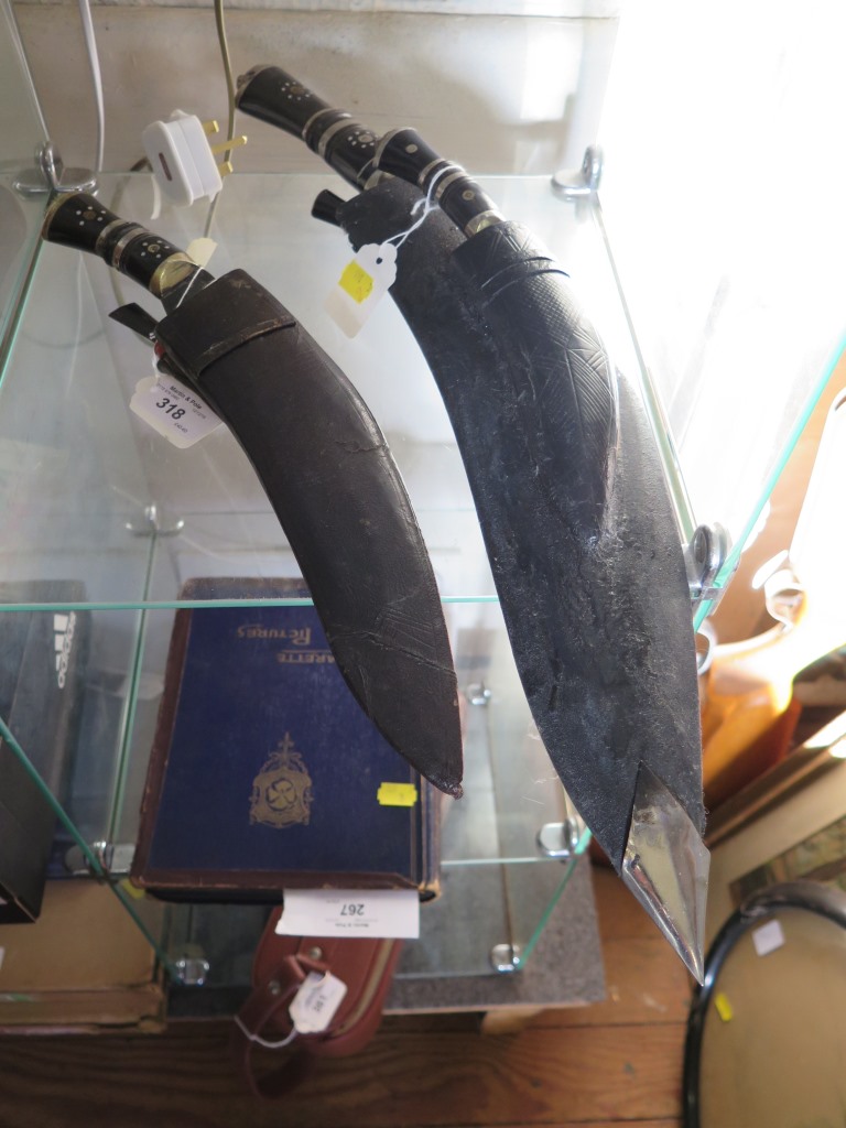 A horn handled Kukri, with leather scabbard mounted with small knife and two sharpening blades,