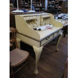 A cream painted desk, the top with pigeon holes and drawers over two frieze drawers on cabriole legs