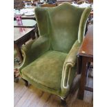 A George III green upholstered wing armchair on cabriole legs