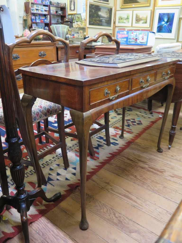 A crossbanded walnut side table, with three frieze drawers and moulded apron on cabriole legs and