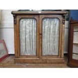 A mid Victorian walnut chiffonier, with twin glazed doors and carved corbels on a plinth base,
