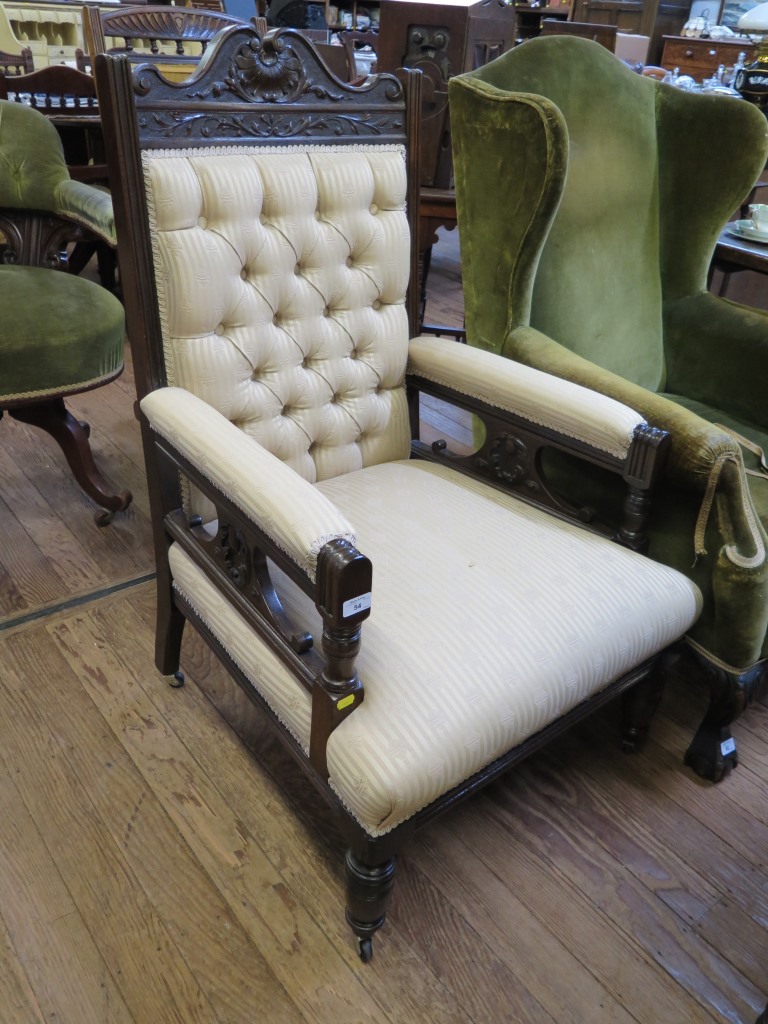 A late Victorian carved gentleman's armchair with button back striped upholstery on ring turned