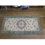 A pair of ivory and green rugs with flowerhead decoration 135cm x 70cm