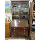 A 1930s mahogany bureau bookcase, with arched glazing bars over a sloping fall enclosing pigeon