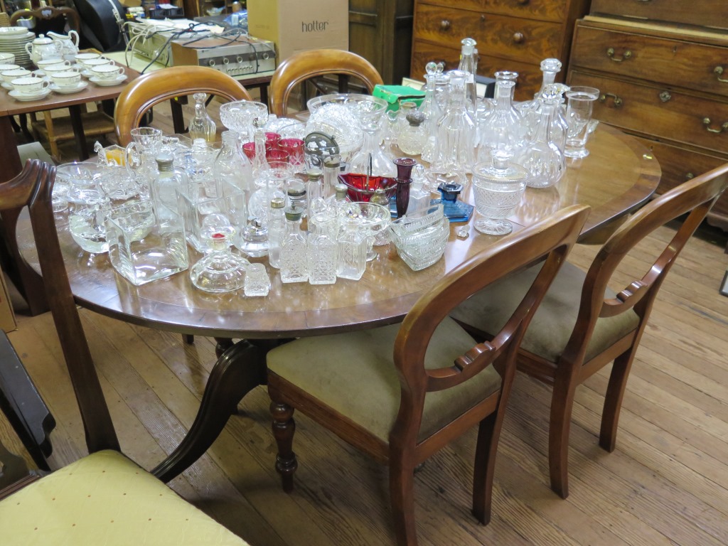 A twin pedestal crossbanded mahogany dining table, with tripod legs and brass paw feet, one extra