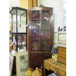 A tall early Victorian mahogany corner cabinet, the scroll carved pediment over a pair of glazed