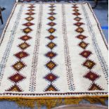 A MOROCCAN CREAM GROUND RUG with three rows of diamond motifs 155cm x 234cm