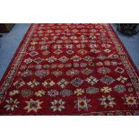 A 20TH CENTURY MOROCCAN RED GROUND RUG of geometric pattern design and fringed edges, 295cm x 202cm