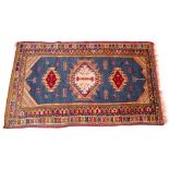 A MIDDLE EASTERN BLUE AND RED GROUND WOOLEN RUG with a banded border and geometric decoration