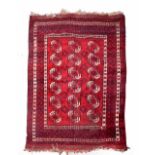 AN AFGHAN DARK RED GROUND CARPET decorated with three rows of polygons within a multiple border,