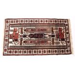 A PERSIAN RUST GROUND RUG with central stylised figural decoration and a banded border 106cm x 200cm