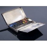 A SILVER ARTISTS TRAVELLING WATERCOLOUR PAINT BOX with monogram engraved decoration to the lid, with