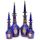 FOUR COBALT BLUE GLASS DECANTERS with gilt painted decoration, the tallest two 48cm high, the