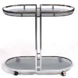 A MID TO LATE 20TH CENTURY CHROME AND GLASS ART DECO STYLE DRINKS TROLLEY with rounded ends and on