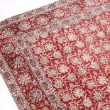 A RED GROUND INDIAN BATIK TYPE FLOWER DECORATED BED COVER 271cm x 176cm