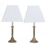 A PAIR OF GILT METAL TABLE LAMPS with reeded column supports and circular spreading bases, each with