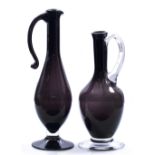 AN AMETHYST COLOURED GLASS EWER 32cm high together with a smaller amethyst coloured glass ewer (2)