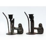 A PAIR OF 20TH CENTURY CAST METAL CANDLESTICKS in the form of monkeys holding banana leaves on