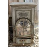 A CAST METAL STOVE with arching door and ash pan beneath, cast with a classical urn to the front and