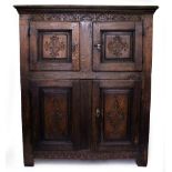 A 17TH CENTURY STYLE OAK CUPBOARD with fielded panel doors above and below and with decorative